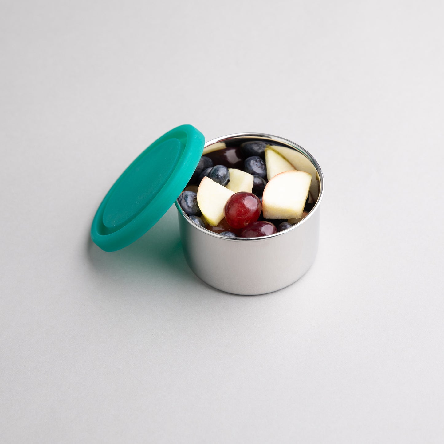 RVS snackbox gevuld met fruit met een groenen siliconen deksel