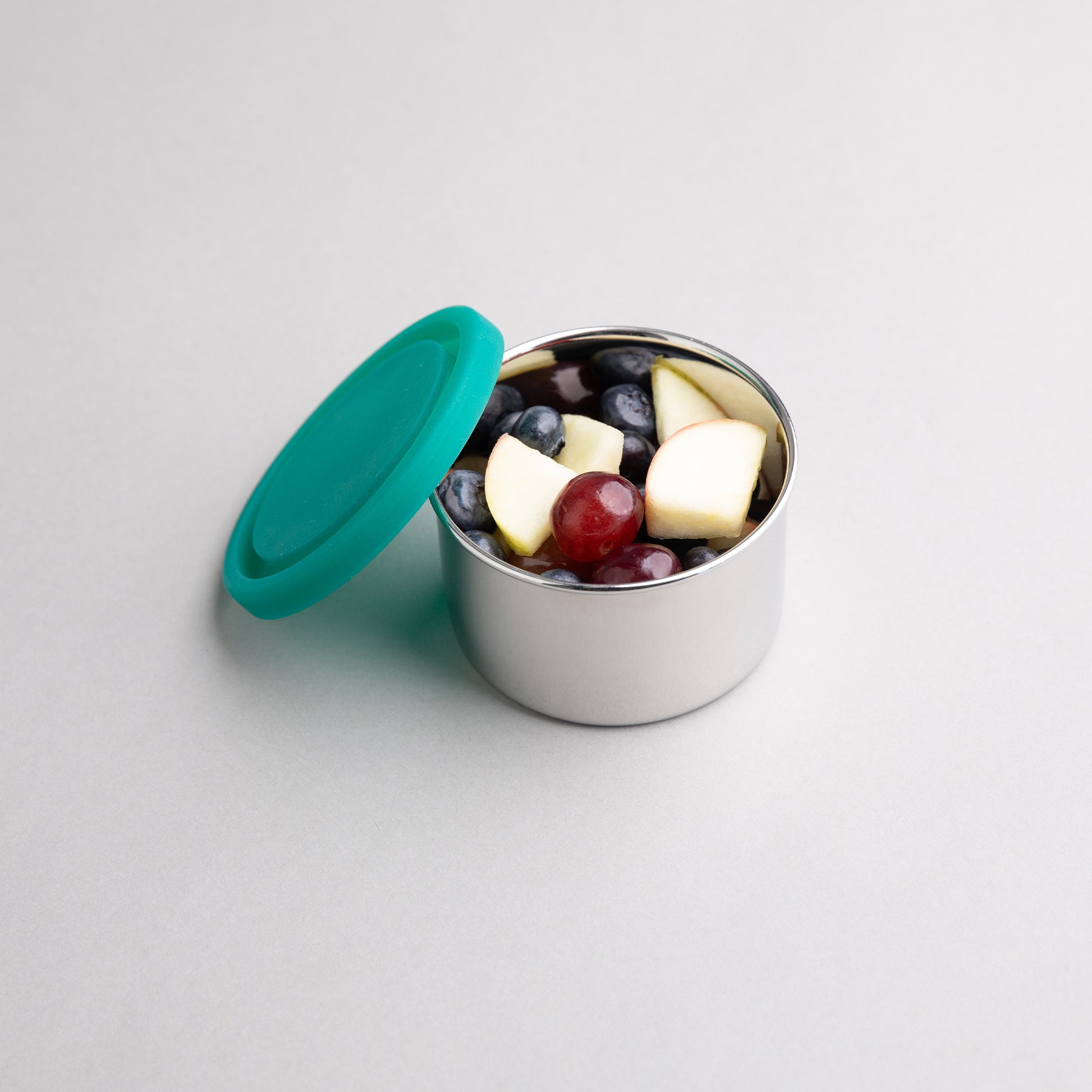 RVS snackbox gevuld met fruit met een groenen siliconen deksel