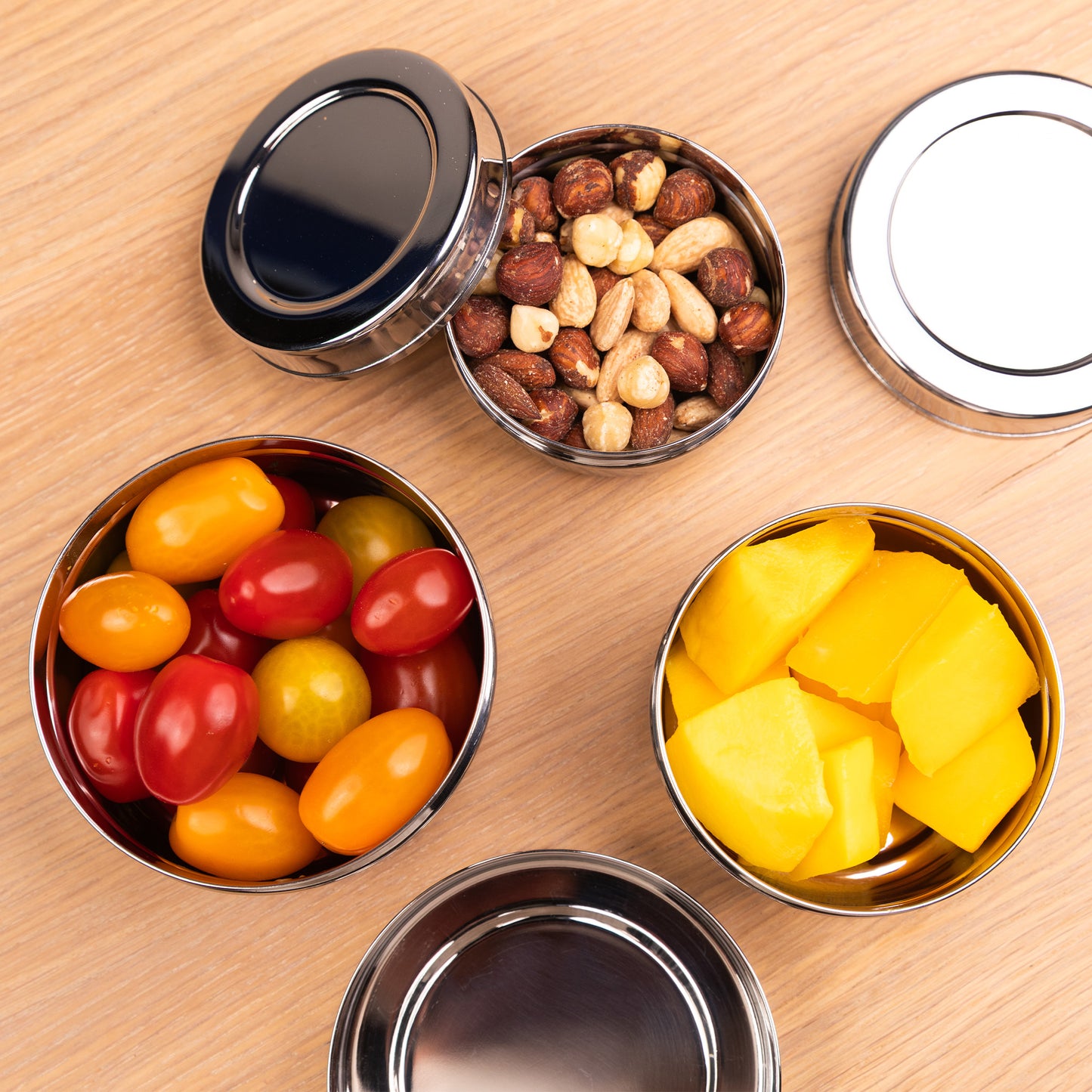 RVS snackboxen gevuld met noten, tomaten en mango