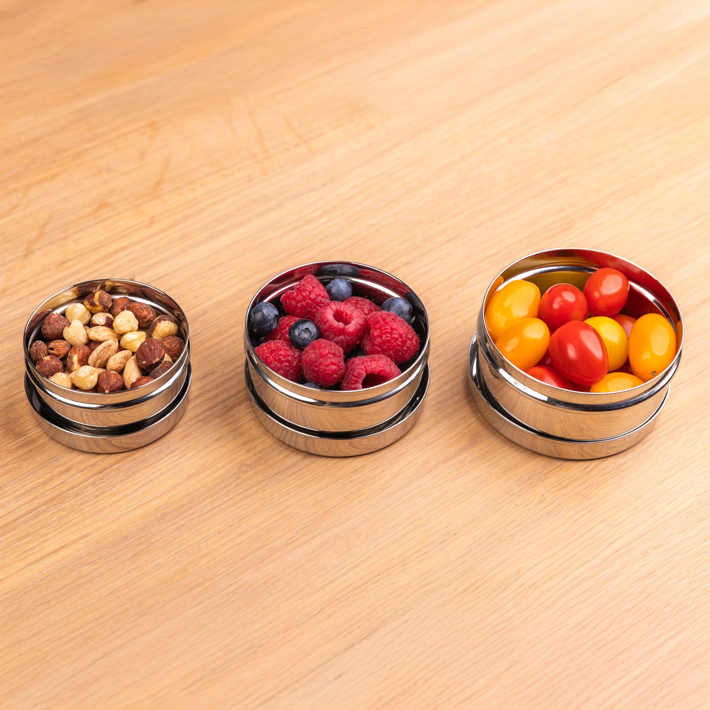 3 RVS snackboxen op een rijtje gevuld met groente en fruit