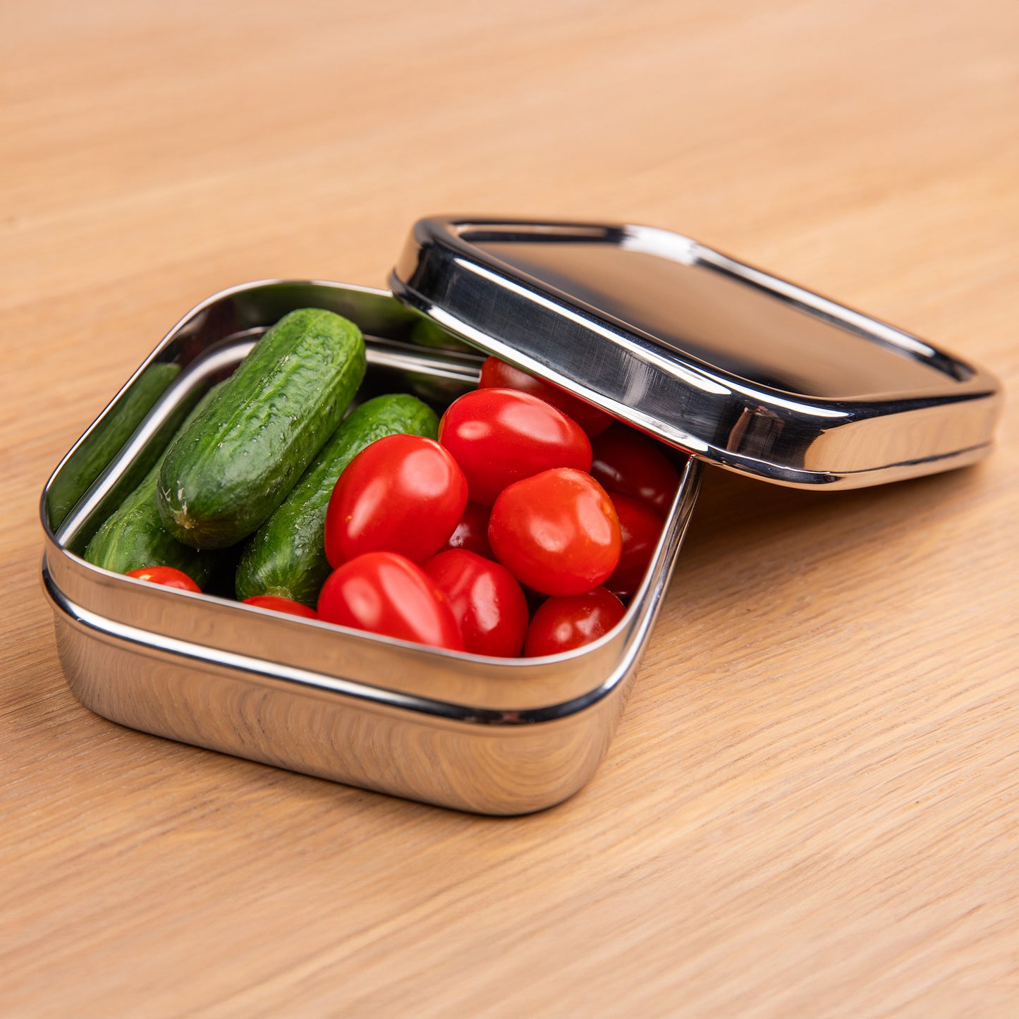 RVS snackbox gevuld met komkommer en tomaat.