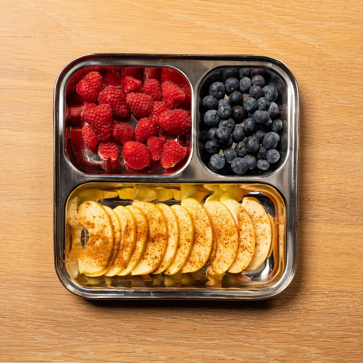 boven aanzicht rvs kinder bord met vakken. gevuld met appel en framboos